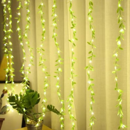 Decorative string lights shaped like vines hanging against a curtain.