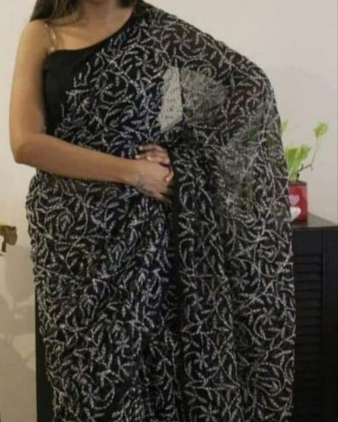 A woman showcasing a red and white georgette saree with Lucknow Chikankari and Tepchi hand embroidery work all over.