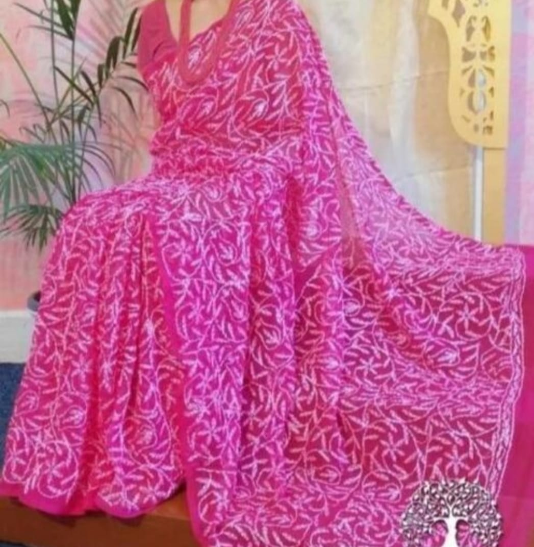 A woman showcasing a red and white georgette saree with Lucknow Chikankari and Tepchi hand embroidery work all over.