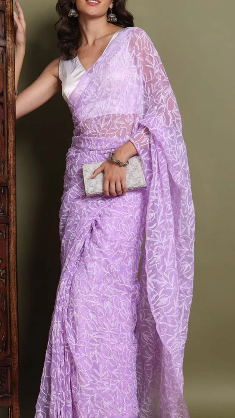 Woman wearing a light purple saree with a white blouse against a green background