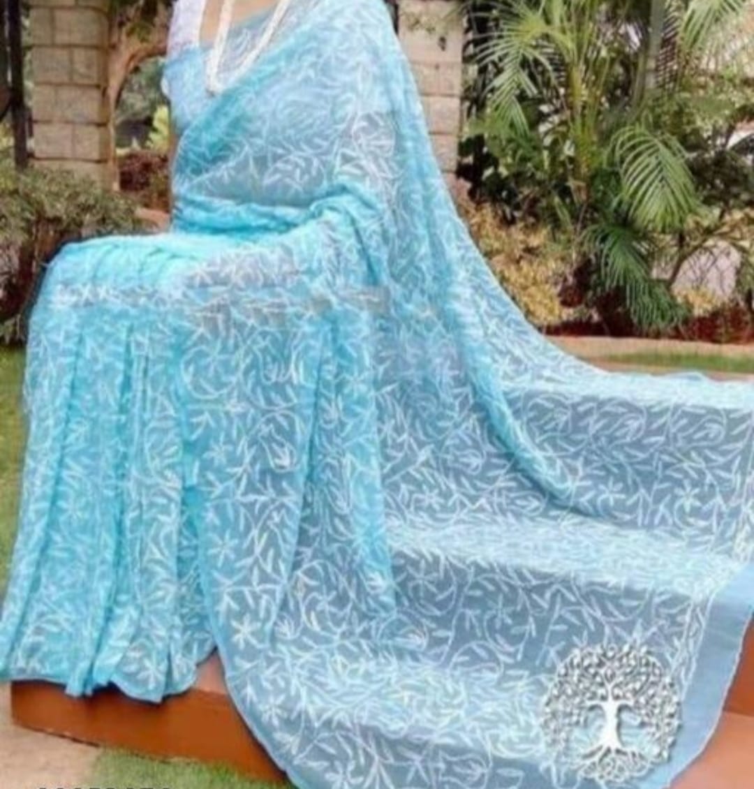 A woman showcasing a red and white georgette saree with Lucknow Chikankari and Tepchi hand embroidery work all over.