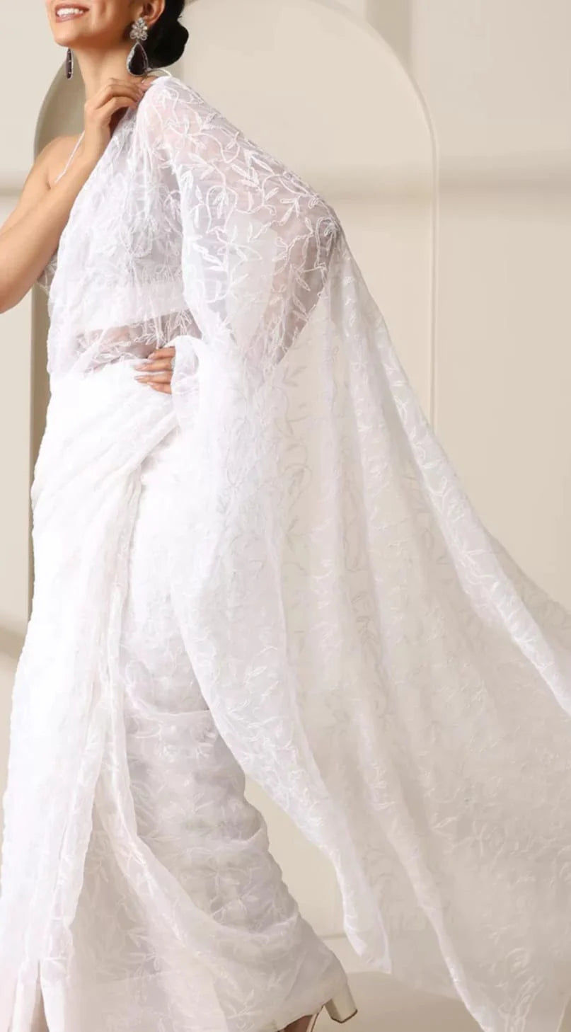 Woman wearing a white saree with a plain background